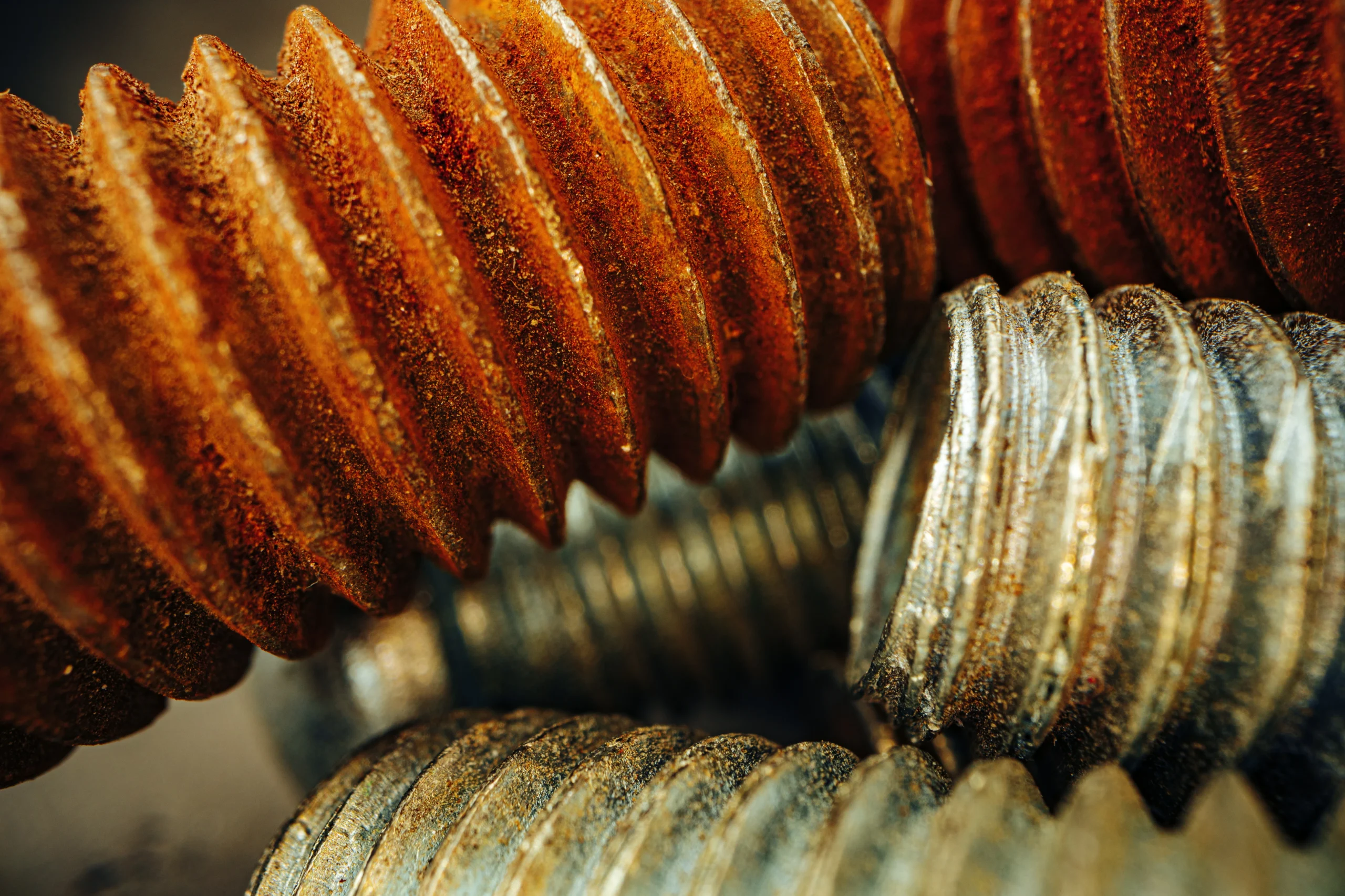 Close-up of several threaded metal bolts, some covered with rust and others clean and metallic, showing contrasting surfaces and textures.